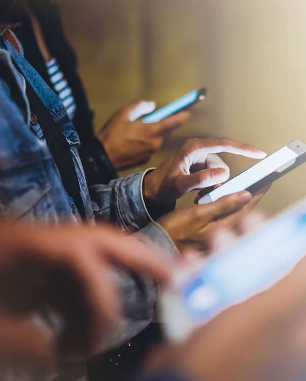 close up of three people using cellphones focused on hands