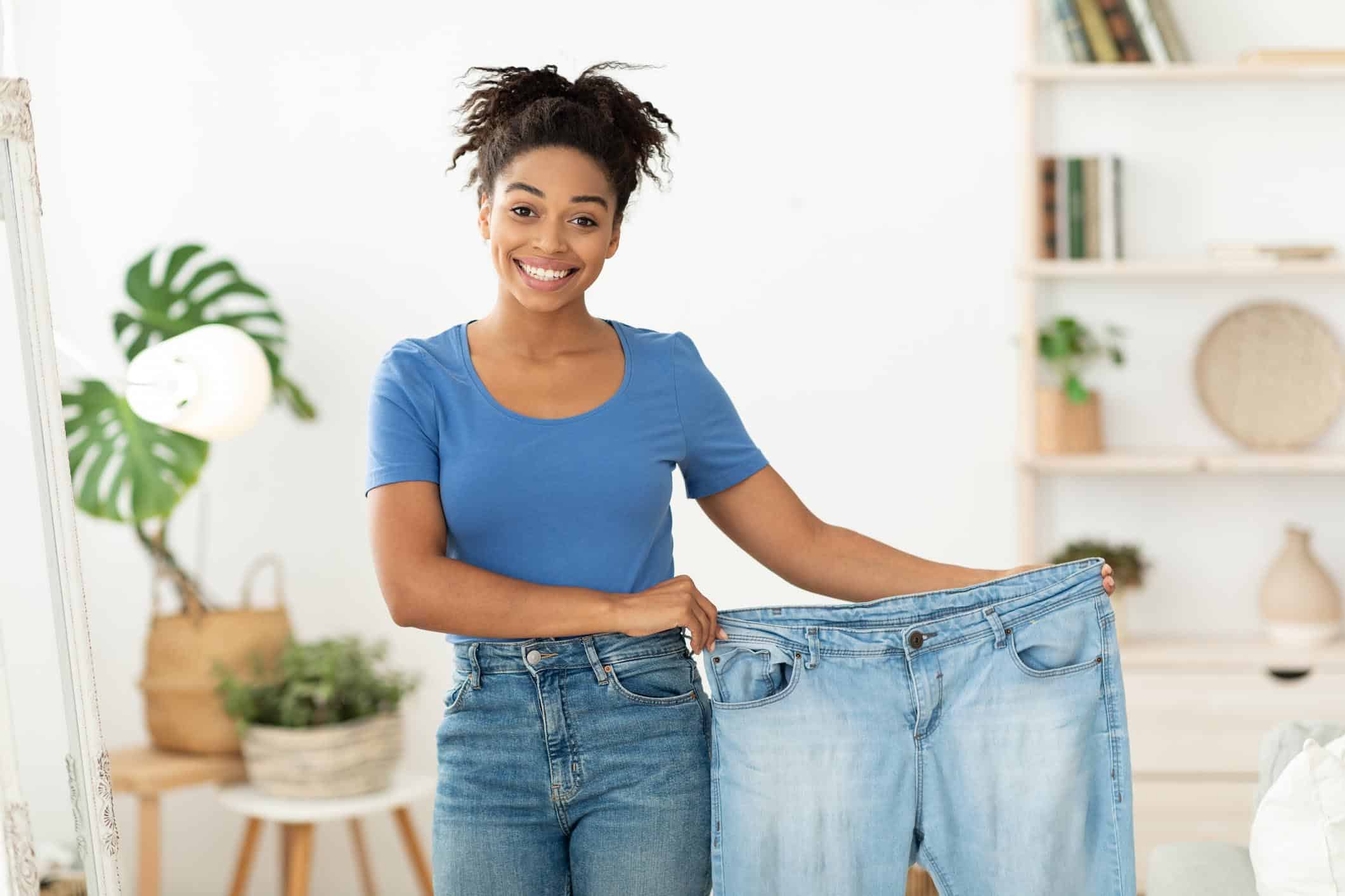 woman holding pants that are too big for her next to her waist